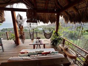 A wooden deck with a hammock, a table, and a sofa with cushions.