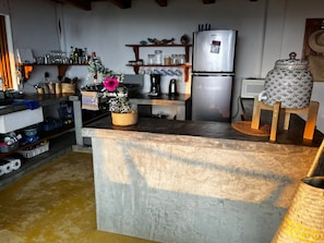 Una cocina con una isla central, electrodomésticos de acero inoxidable y distintos utensilios de cocina en estantes.