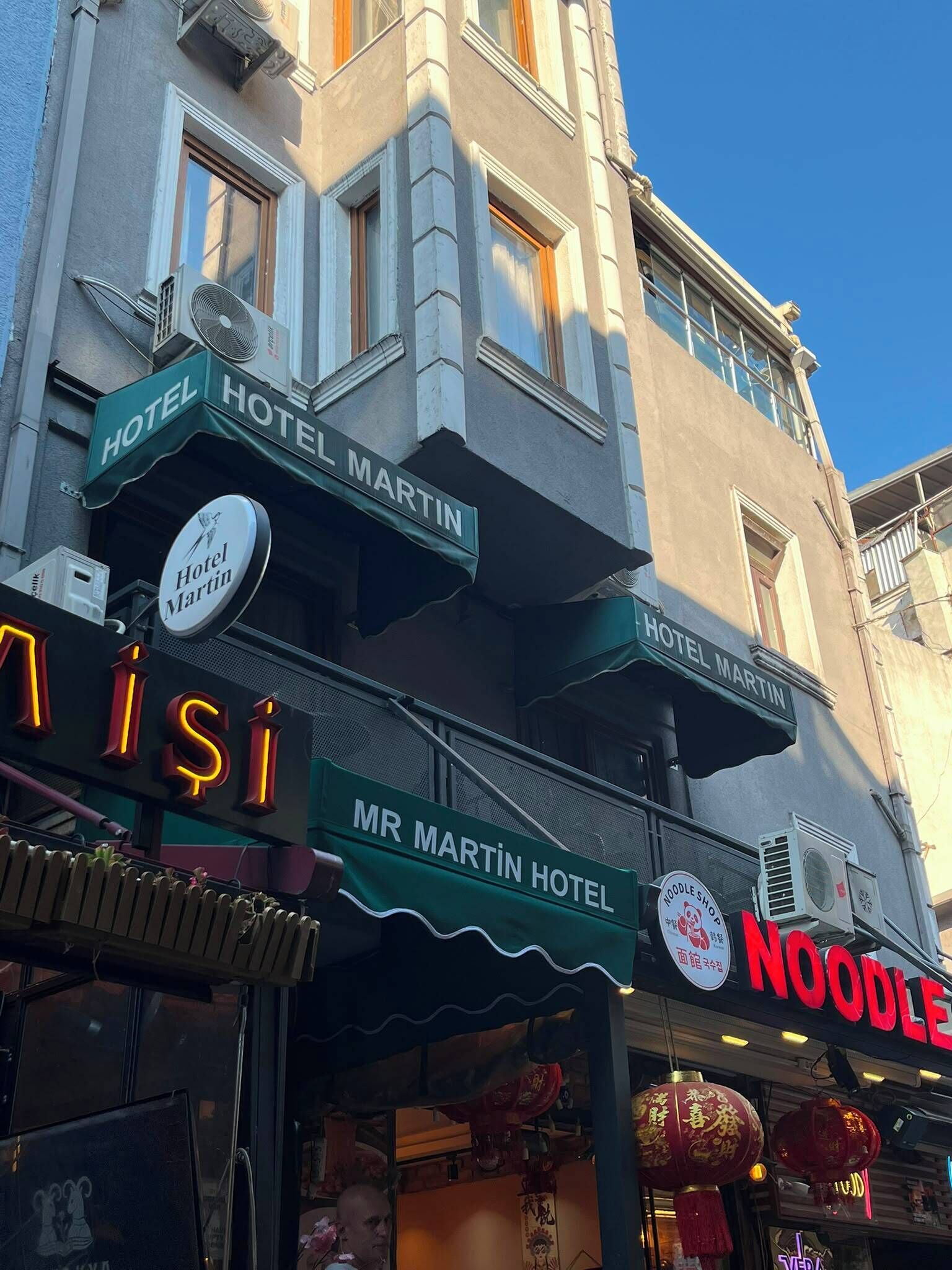 Un edificio con varios letreros de Hotel Martin y Noodle Shop.