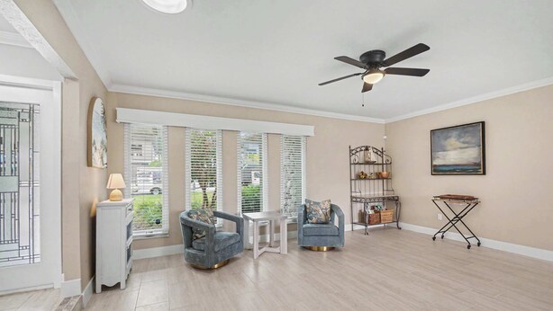 A spacious room with a ceiling fan, a dining table, two chairs, a small side table, and a window with blinds. - North Shore Escape | Heated Pool & Saltwater Canal (North Fort Myers)