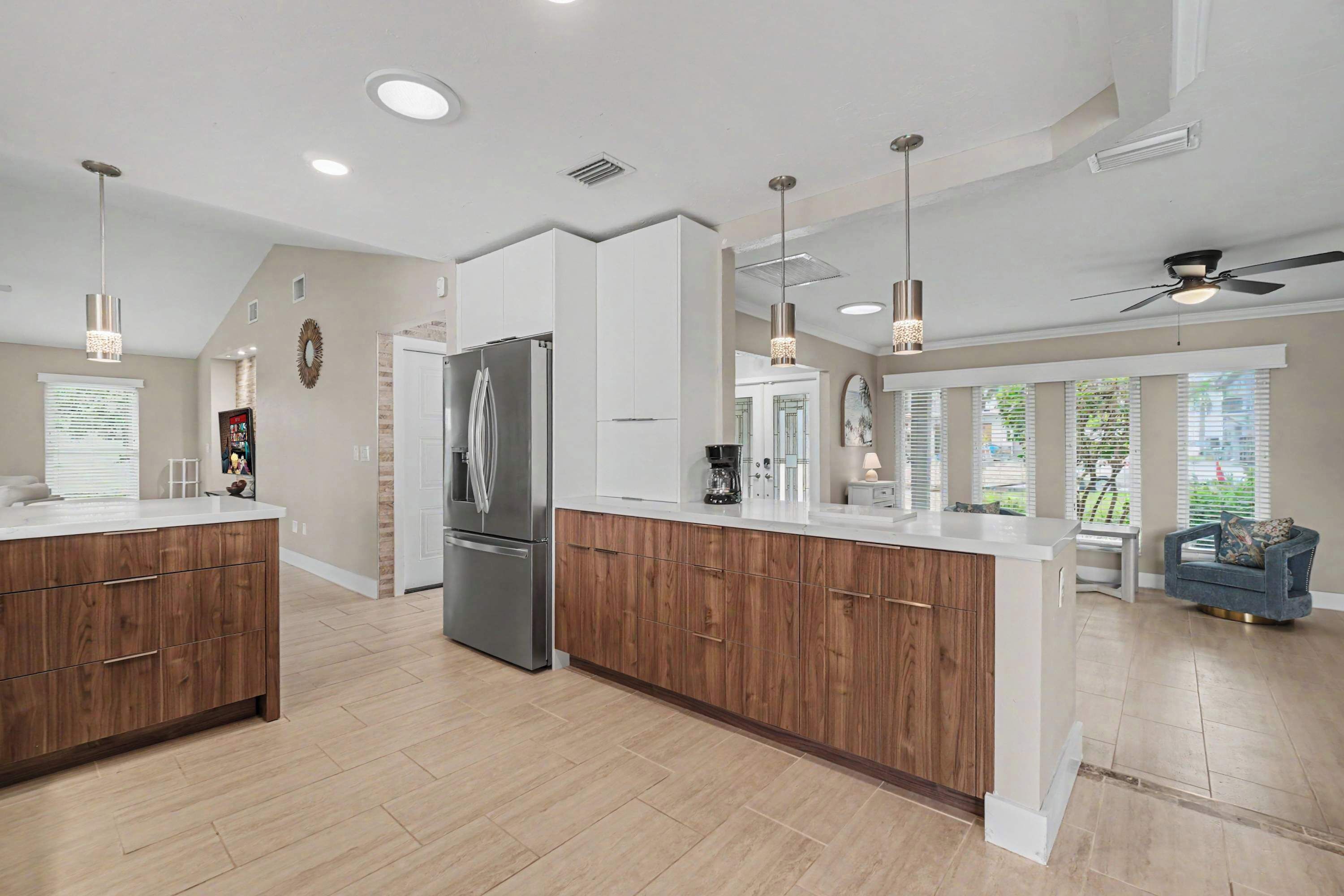 A modern kitchen with a central island, wooden cabinets, and a stainless steel refrigerator.