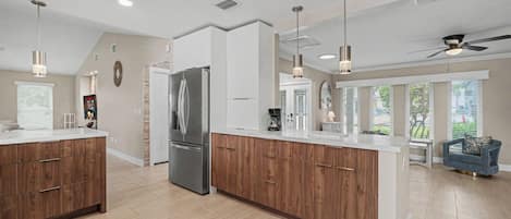 Une cuisine moderne dotée d’un îlot central, de meubles en bois et d’un réfrigérateur en acier inoxydable.