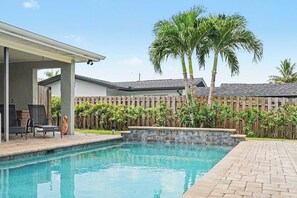 A backyard with a swimming pool, a covered patio area, and a wooden fence. - North Shore Escape | Heated Pool & Saltwater Canal (North Fort Myers)