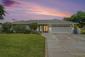 A single-story house with a garage, a well-maintained lawn, and a clear sky. - North Shore Escape | Heated Pool & Saltwater Canal (North Fort Myers)