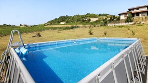 Una piscina con estructura metálica, una escalera y un flotador inflable azul.