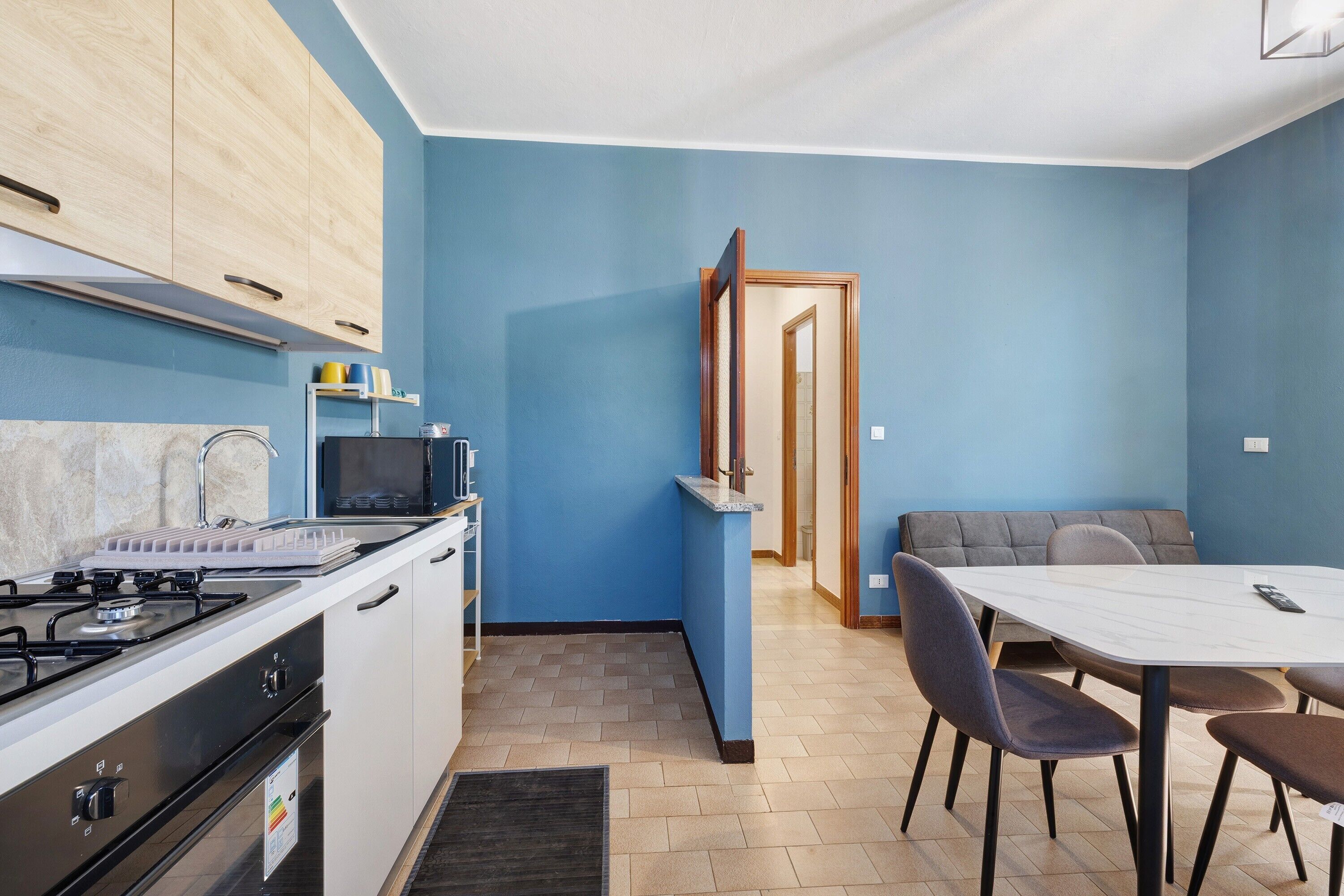 A compact kitchen with a gas stove, microwave, and cabinets. There's a dining area with a table and chairs.