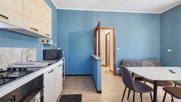 A compact kitchen with a gas stove, microwave, and cabinets. There's a dining area with a table and chairs.
