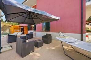 An outdoor patio with wicker furniture, a hammock, and a large umbrella.