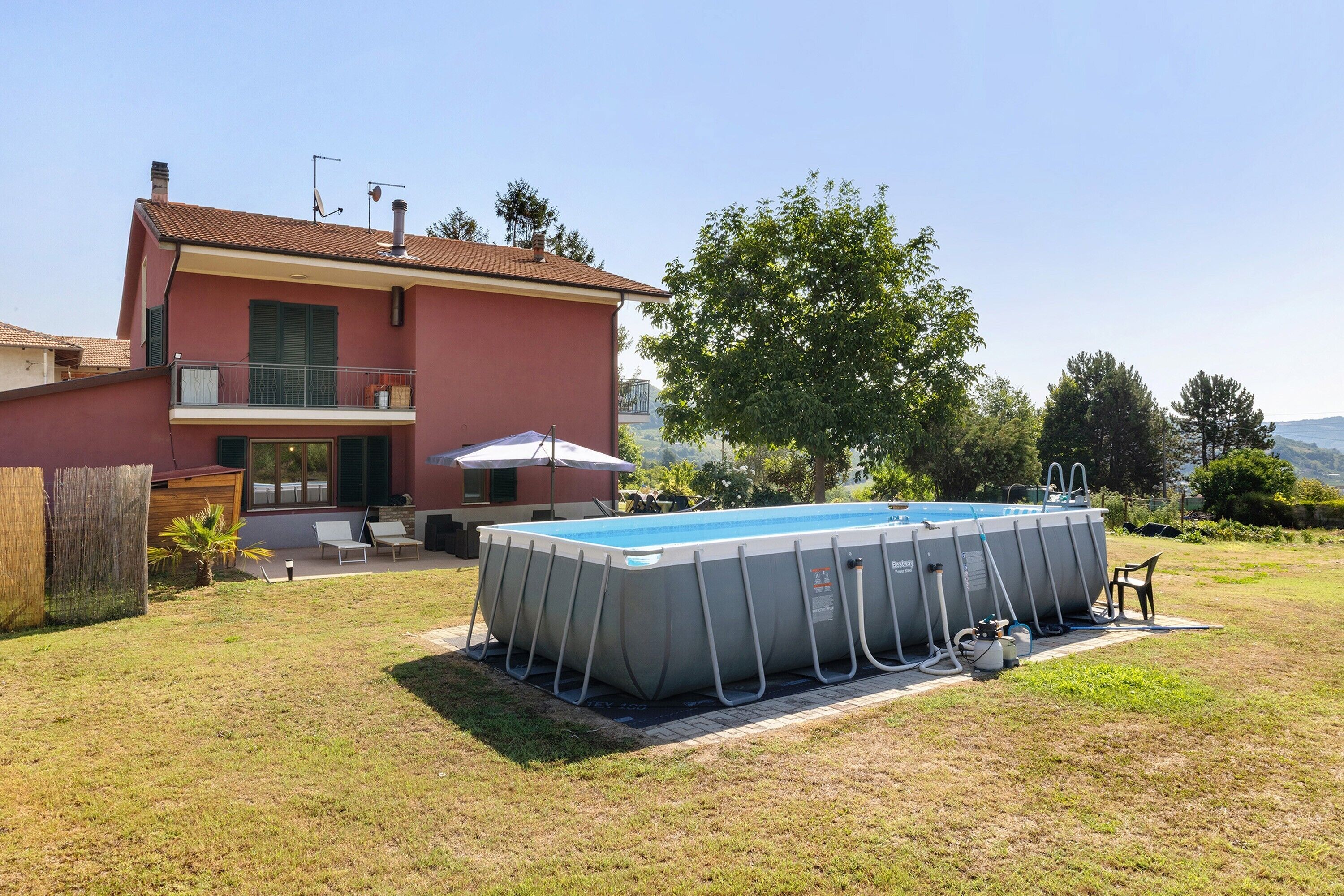 A residential property with a swimming pool, a two-story house, and a clear view of the surrounding landscape.