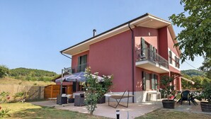 Una casa de dos pisos con balcón, mobiliario exterior y jardín.