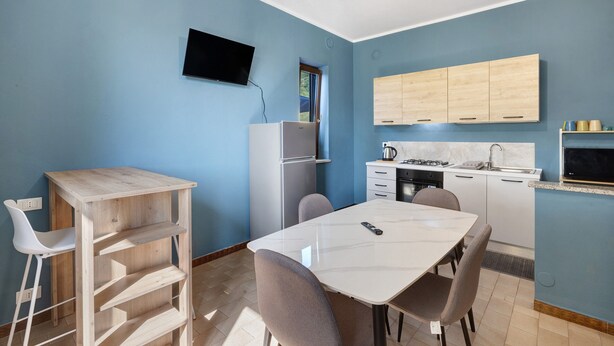 Una cocina compacta con zona de comedor, un televisor en la pared y un ventanal que proporciona luz natural.