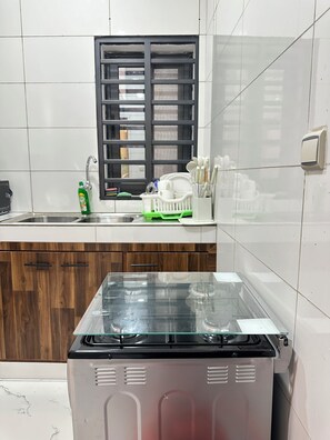 A kitchen with a stainless steel stove, a window with blinds, a dish rack, and a faucet. - A chic and cozy apartment in the heart of Cotonou (Cotonou)