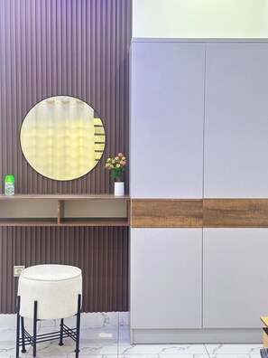 Ein modernes Badezimmer mit rundem Spiegel, einem kleinen Waschbecken, einer Toilette und einem Waschtisch mit Spiegel.