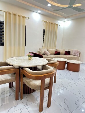 A modern living room with a round marble table, beige sofas, and a ceiling fan. - A chic and cozy apartment in the heart of Cotonou (Cotonou)