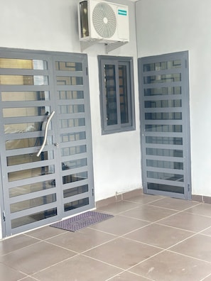 A room with two grey doors, a window, and an air conditioning unit mounted on the wall. - A chic and cozy apartment in the heart of Cotonou (Cotonou)
