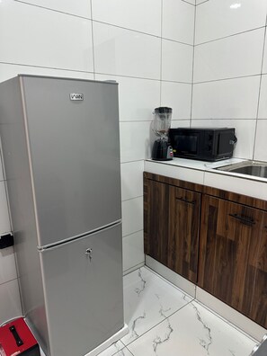 Eine Küche mit einem Edelstahl-Kühlschrank, einer Mikrowelle und Holzschränken.