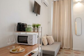 A compact living space with a kitchenette, a sofa, and a television mounted on the wall. - City Hub 1 | Boutique Studio in Bari's Historic Heart (Bari)