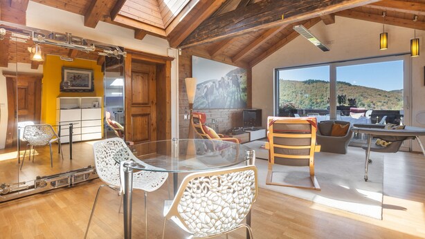 A modern interior with a glass dining table, wooden chairs, a fireplace, and a large window offering a view of the outdoors. - Apartment "Weiser Hirsch" in Chalet Burgblick with Castle Views and Modern Comfort (Weilrod)