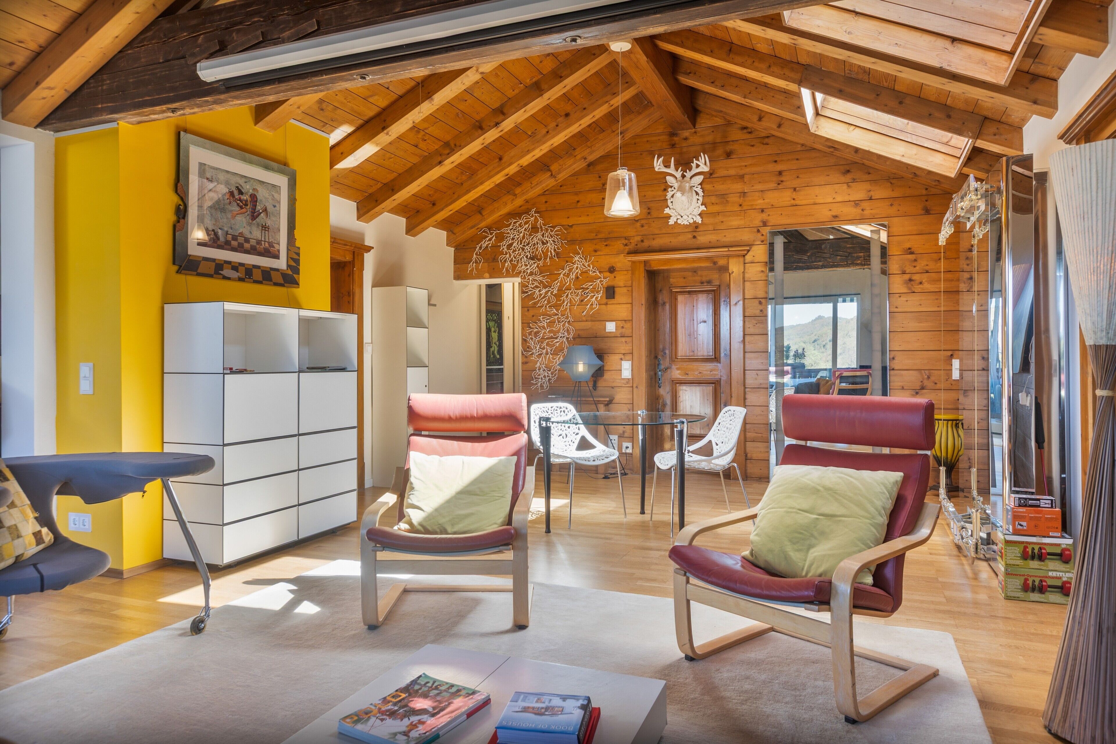 Un intérieur chaleureux avec des poutres en bois, un coin repas et une vue par la fenêtre.