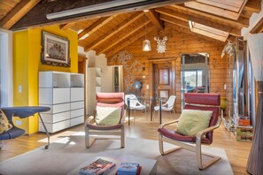 Un interior acollidor amb bigues de fusta, zona de menjador i vista per la finestra.