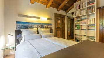 Een slaapkamer met een bed, een boekenkast en een schilderij aan de muur.