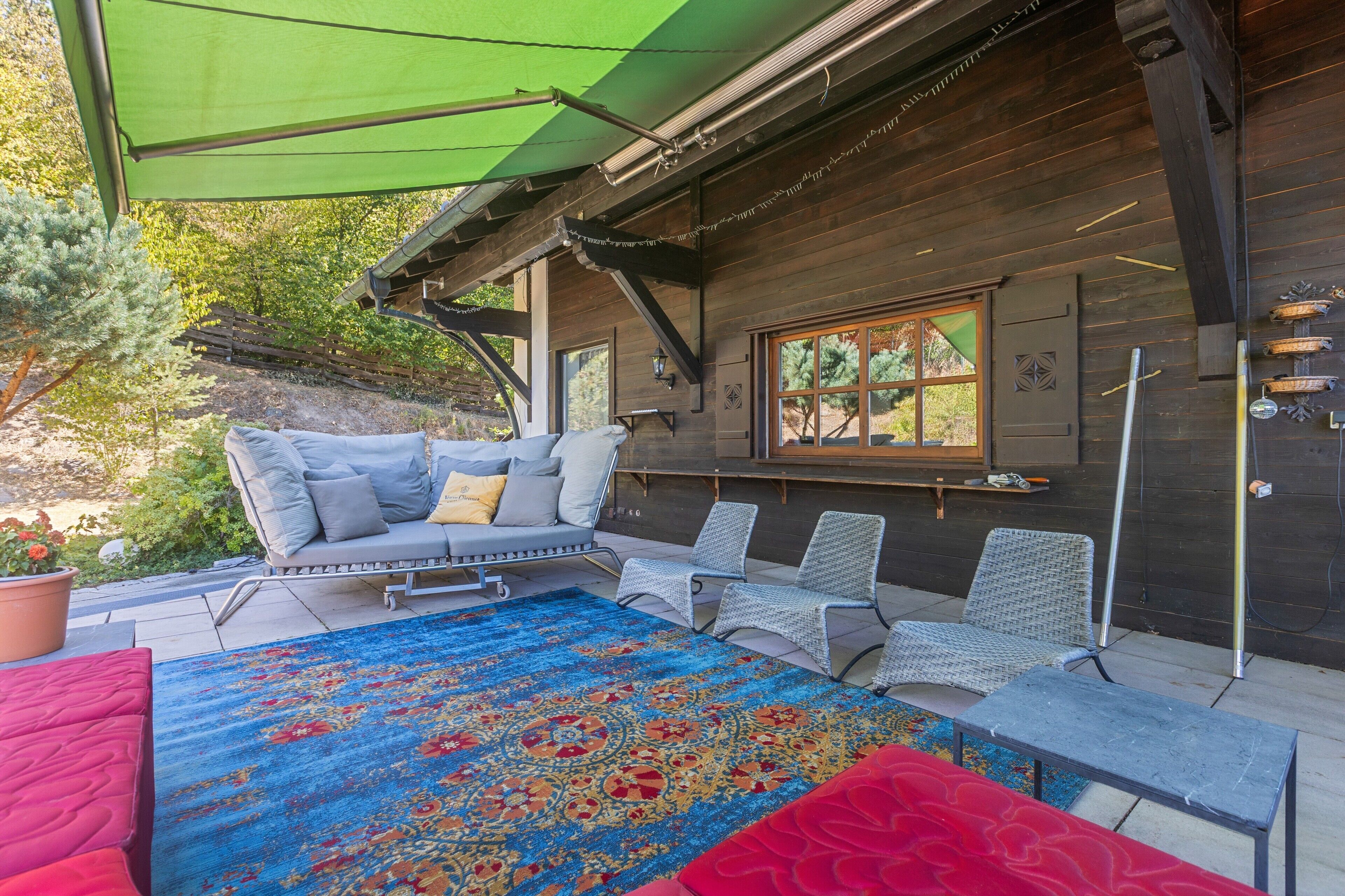 Ein gemütlicher Außenbereich mit einer Couch, Stühlen und einem gemusterten Teppich.
