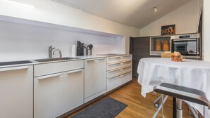 A modern kitchen with white cabinetry, a stainless steel sink, and a built-in oven. - Apartment "Weiser Hirsch" in Chalet Burgblick with Castle Views and Modern Comfort (Weilrod)