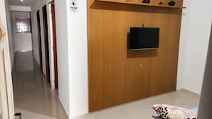 Una sala de estar moderna con una pared de acento de madera, un televisor de pantalla plana y un estante con objetos decorativos.