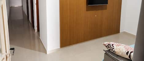Una sala de estar moderna con una pared de acento de madera, un televisor de pantalla plana y un estante con objetos decorativos.