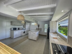 A modern kitchen with a central island, built-in appliances, and a large window offering a view of greenery. - 800m beach - Villa pool & spa - 6 ad + 1 child (Saint-François)