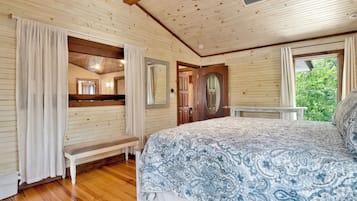 Une chambre dans une cabane en bois, avec un lit, un banc et une porte donnant sur une autre pièce.
