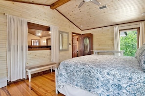 A wooden cabin bedroom with a bed, bench, and a door leading to another room. - "Catican Bayou" Fish River Waterfront Home 3 bedrooms; 5 bathrooms  Kayaks (Summerdale)