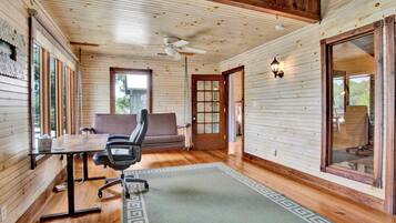Un intérieur en bois comprenant un bureau, une chaise, un canapé et un ventilateur de plafond.