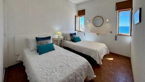 Una habitación con dos camas, una mesita, un espejo y una ventana con vistas.