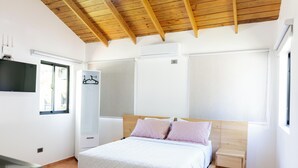 Quarto com cama, guarda-roupa, televisão e janela.