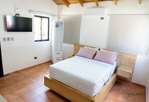 Um quarto com cama, guarda-roupa, televisão e janela.