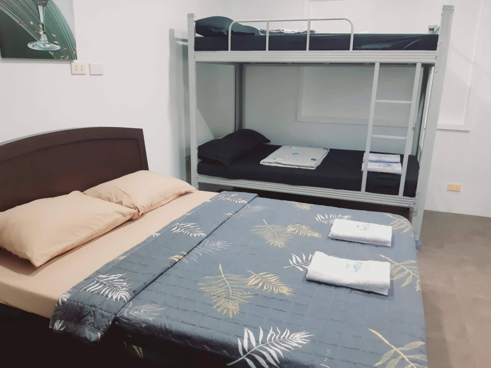 A bunk bed with a lower bed and a top bunk. There is a bed on the left with a headboard and pillows.