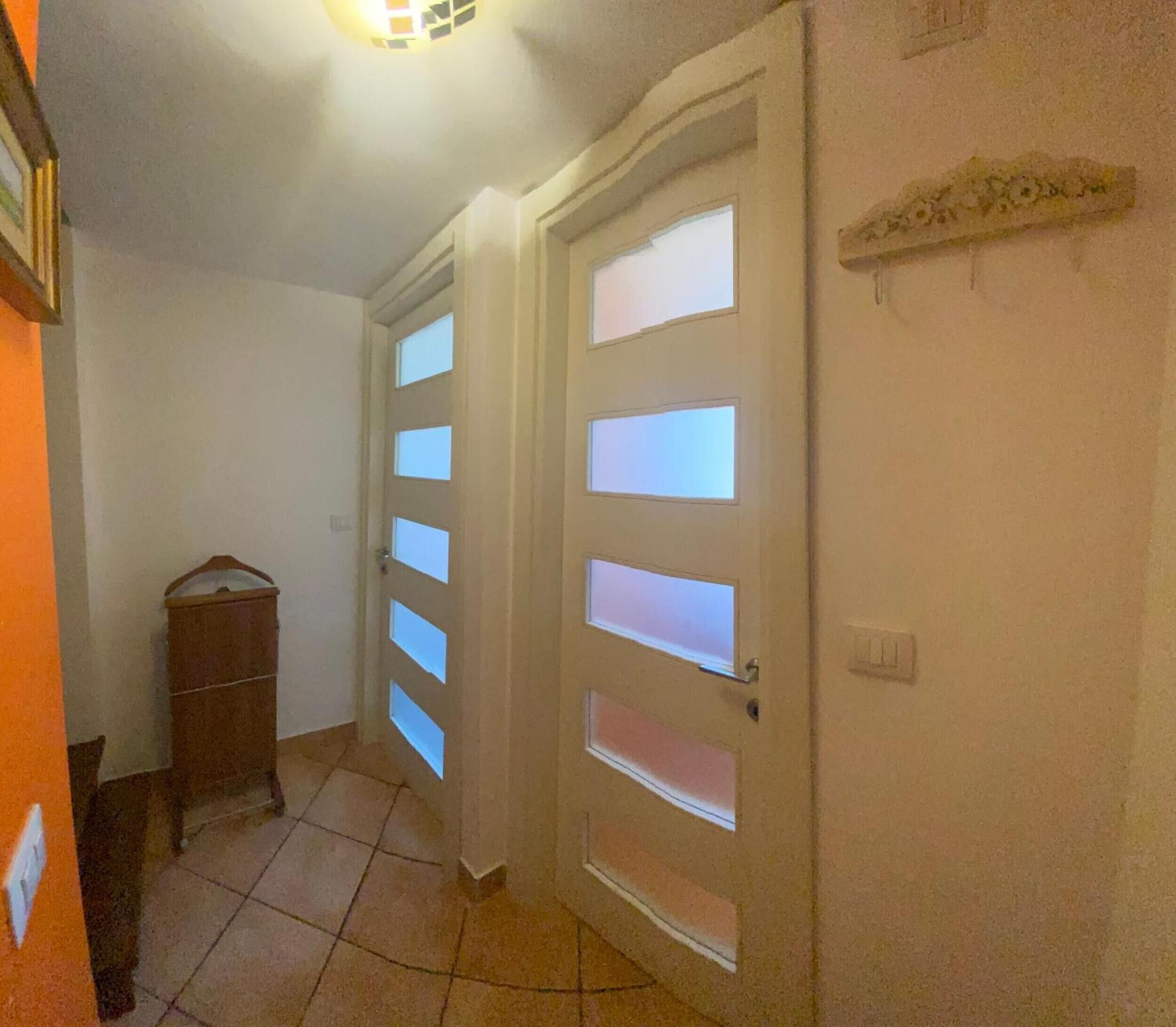 Ein Flur mit einem Holzschrank und einer Wandregal.