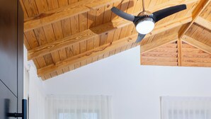 Uma sala de estar com sofá em seção, mesa de centro, ventilador de teto e teto de madeira.