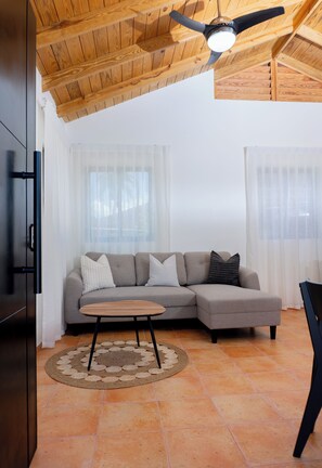 Ein Wohnzimmer mit Ecksofa, Couchtisch, Deckenventilator und Holzboden.
