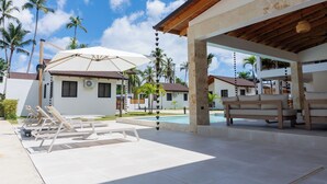 Resort com piscina, espreguiçadeiras e área de estar coberta.