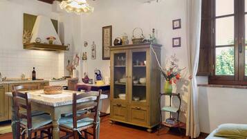 A traditional kitchen with a dining area, wooden cabinets, and a window with curtains.