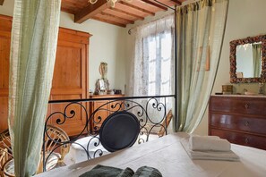 Quarto com cama, cômoda, espelho e janela com cortinas.