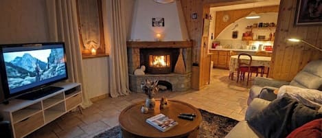 Ein gemütliches Wohnzimmer mit Kamin, Fernseher und einer bequemen Sitzecke.