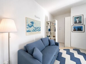 A modern living room with a blue sofa, a lamp, and artwork on the walls. - BeHappyM • Fair/St. Ursula • Skyview (Bologna)