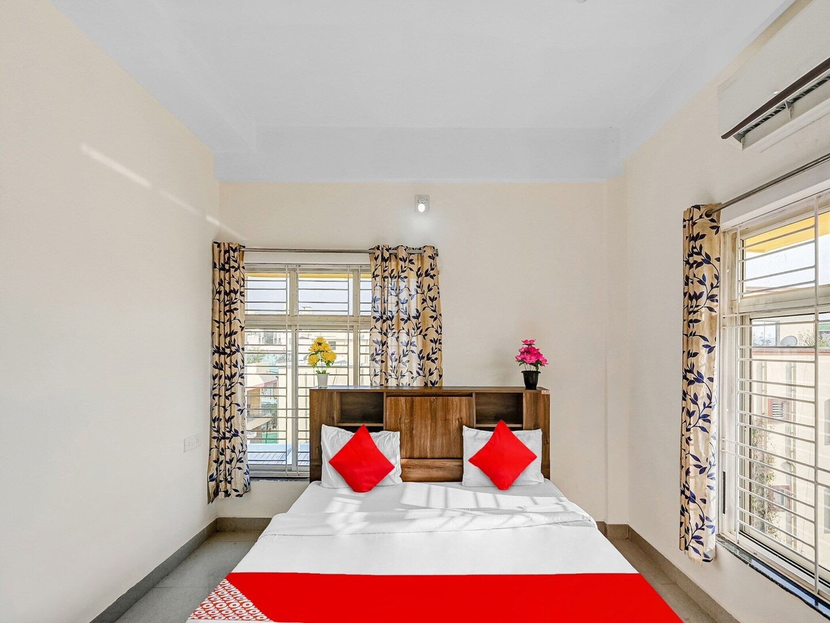 A bedroom with a bed, curtains, a window, and a bedside table.