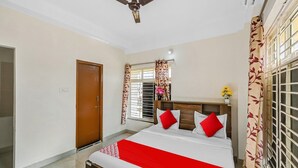 Une chambre à coucher avec un lit, un ventilateur de plafond, une fenêtre avec des rideaux et une porte.