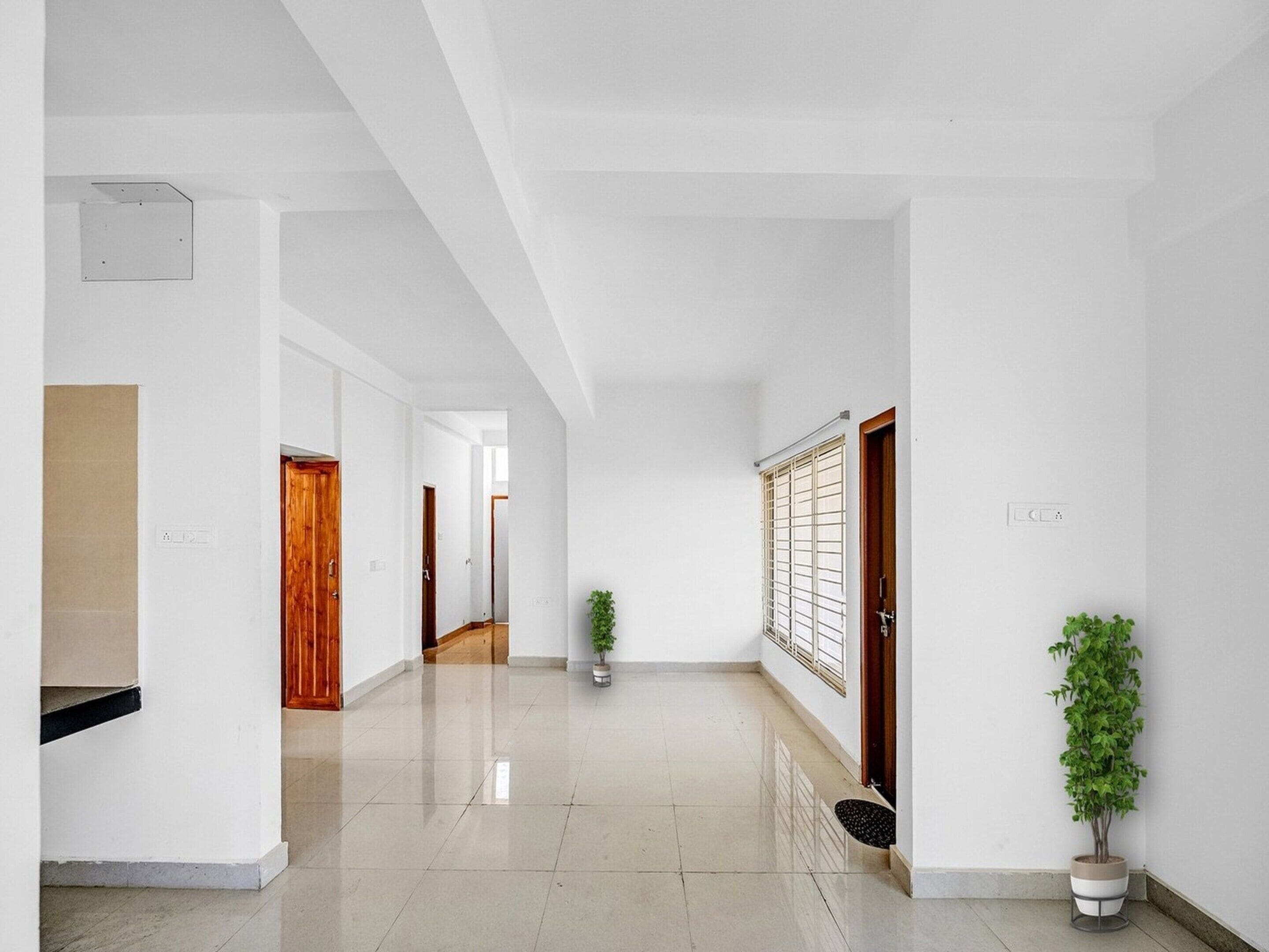 A clean, modern hallway with white walls and a polished floor, leading to multiple doors.