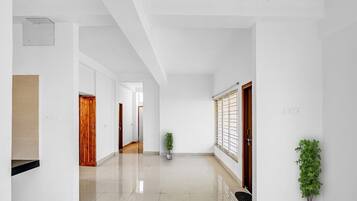 A clean, modern hallway with white walls and a polished floor, leading to multiple doors.