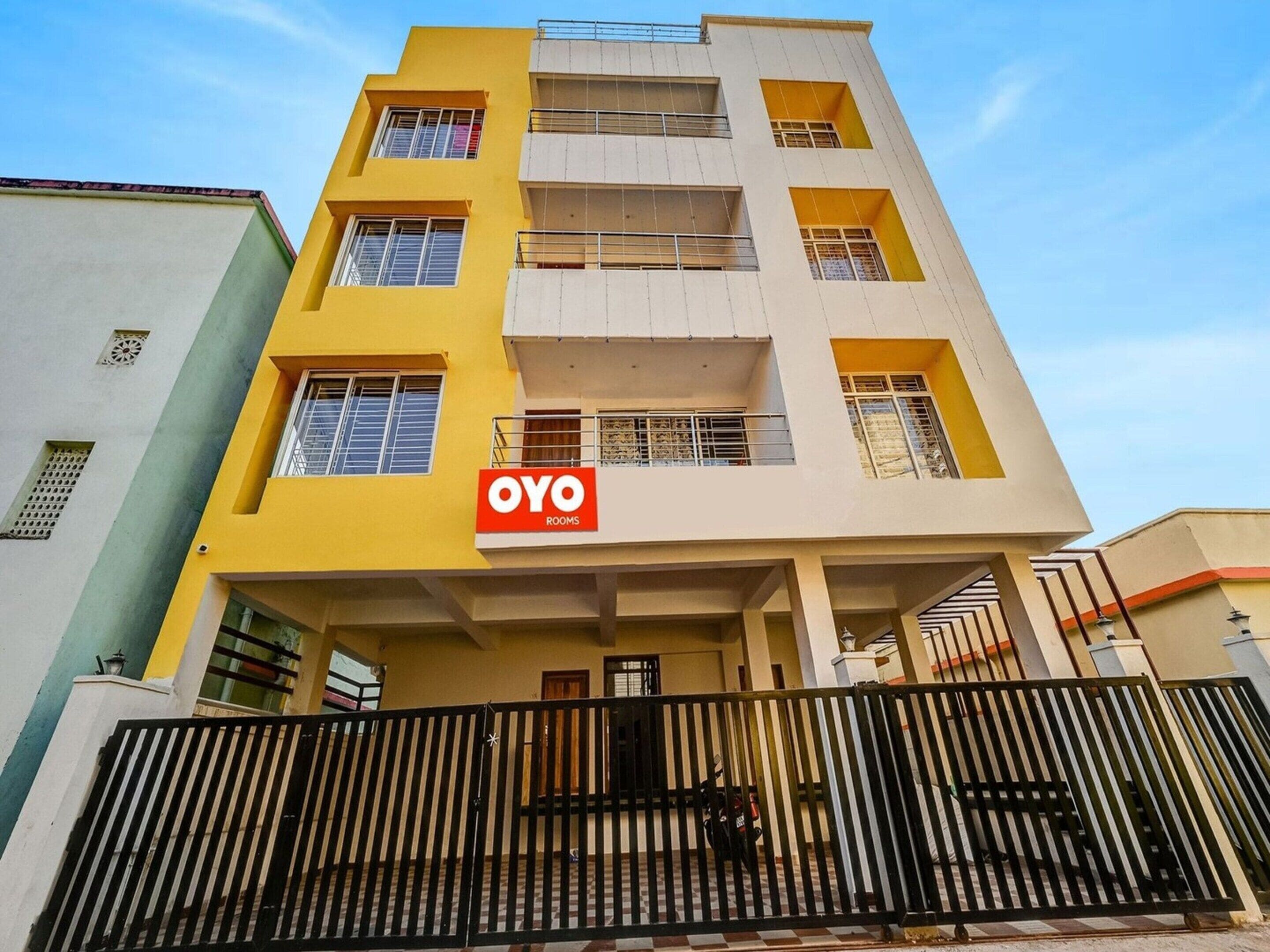 A multi-story building with a yellow facade and a sign for 'OYO ROOMS' indicating a hotel or lodging service.